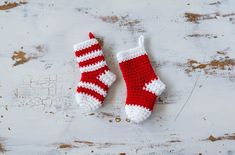 two red and white crocheted christmas stockings on a wooden surface with one laying next to the other