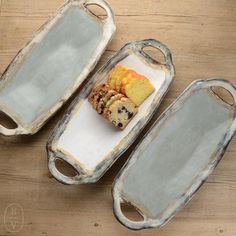 three trays that have cookies in them on top of a wooden table and one is empty