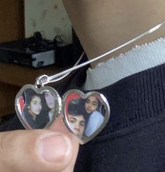 a person holding two heart shaped pendants in their left hand and the other one has an image of three women on it