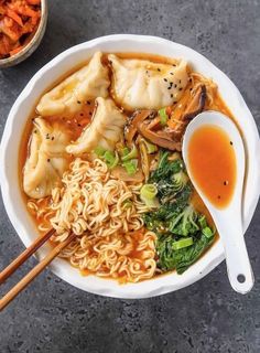 vegan kimchi noodle soup with dumplings in a white bowl and chopsticks