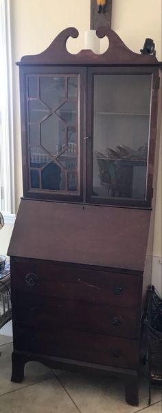 an old wooden desk with glass doors and drawers