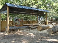 there is a small shelter in the woods with logs on the ground next to it