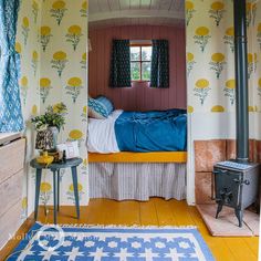 a bed sitting in the middle of a room with yellow and blue wallpaper on it