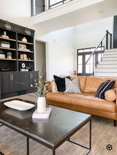 a living room filled with furniture and a fire place next to a stair case in front of a window