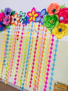 colorful paper flowers and streamers are hanging from the wall