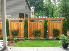 a wooden fence in front of a house with plants growing on the top and bottom