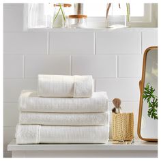 a stack of white towels sitting on top of a counter next to a mirror and brush