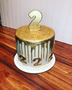 a two tiered cake with white icing and gold sprinkles on top