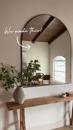 a mirror sitting on top of a wooden table next to a vase filled with flowers