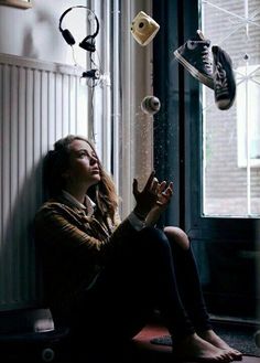 a woman sitting on the floor in front of a window with headphones hanging from it