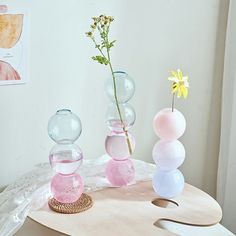 three vases with flowers in them sitting on a table