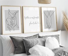 two framed art prints on the wall above a bed with pillows and blankets in front of it