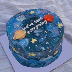 a birthday cake that is on top of a blue tablecloth with stars and planets