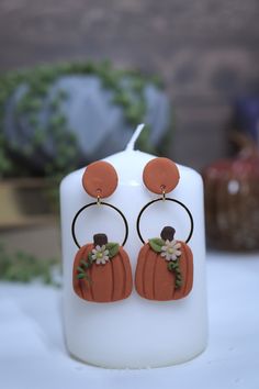 a pair of pumpkins with flowers on them sitting next to a white candle holder