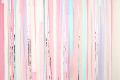 pink, blue and white streamers hanging from the ceiling in front of a wall