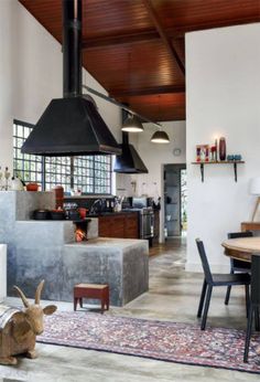 an open kitchen and dining room area with wood flooring, white walls, exposed ceiling, and wooden beams