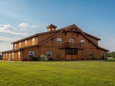 a large brown barn sitting on top of a lush green field