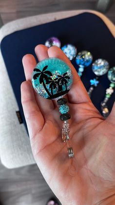 a hand holding a glass bead with a palm tree on it and some beads