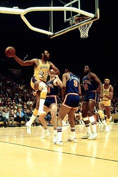 a group of men playing basketball against each other on a court in front of an audience