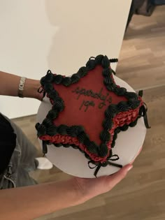 a person holding a cake with the words happy birthday on it in black and red icing