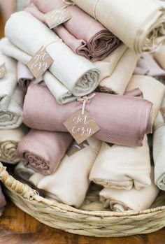 a basket filled with lots of different colored folded cloths on top of a wooden table