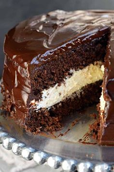 a chocolate cake with white frosting and one slice cut from it on a serving platter