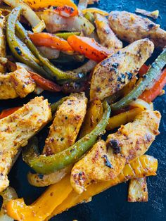 grilled chicken and peppers on a black plate