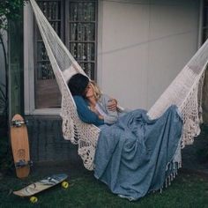 a woman laying in a hammock with her feet up on a skateboard