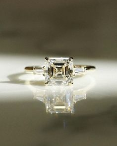 an engagement ring with three baguets on the side, and one stone in the middle