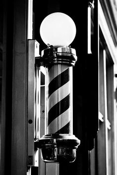 a black and white photo of a street light on the side of a building with stripes