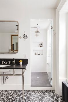 a bathroom with black and white tile flooring, a large mirror above the sink