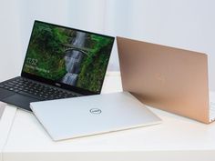 two laptops side by side on a white surface with a waterfall in the background