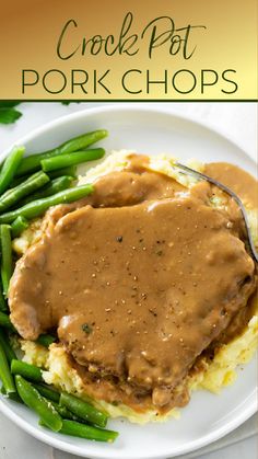 a white plate topped with mashed potatoes covered in gravy and green beans