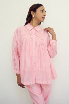 Pink shirt featuring smocked detailing with hand embroidered flower detail and scalloped collar. - Aza Fashions Feminine Cotton Blouse With Smocked Cuffs, Embroidered Tops With Relaxed Fit, Traditional Spring Workwear Tops, Embroidered Spring Tops With Ruffled Collar, Summer Cotton Shirt With Gathered Sleeves, Cotton Shirt With Gathered Sleeves For Spring, Pink Cotton Smock Blouse, Feminine Cotton Tops With Collared Neckline, Feminine Cotton Top With Collared Neckline