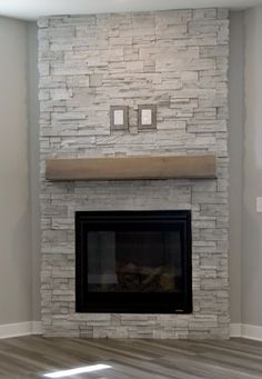 an empty room with a stone fireplace and wood floor