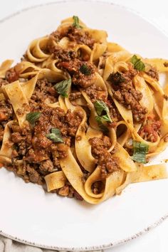 a white plate topped with pasta and meat