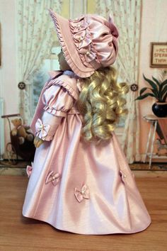 a doll with blonde hair wearing a pink dress and hat