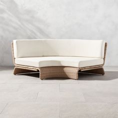 a wicker couch sitting on top of a white tile floor next to a wall