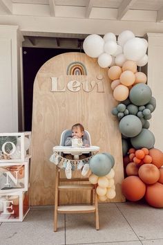 a baby sitting in a high chair next to balloons