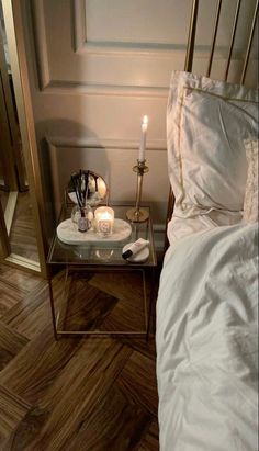 a bed with two candles on top of it next to a glass tray filled with flowers