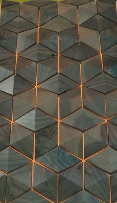 an orange and black clock on top of a wooden wall with hexagonal tiles