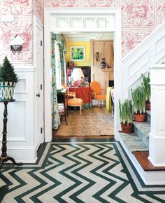 an entry way with pink and green wallpaper on the walls, white stairs and potted plants