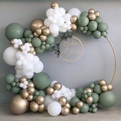 the balloon arch is decorated with gold, white and green balloons