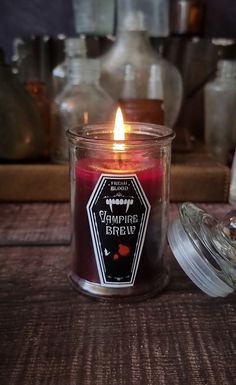 a candle sitting on top of a table next to some glass jars and containers filled with liquid