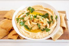 hummus and pita chips on a cutting board