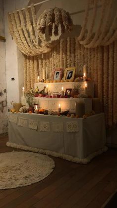 a table with candles and pictures on it in front of a wall hanging from the ceiling