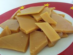 a white plate topped with pieces of cheese on top of a red and white table