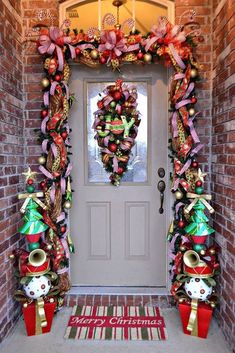 a christmas wreath on the front door of a brick house with bells and ornaments around it