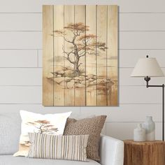 a living room scene with focus on the couch and wall art that has a tree painted on it