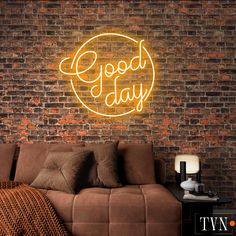 a brick wall with a neon sign that says good day on it and a couch in the foreground